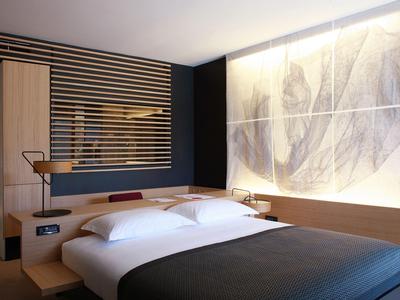 Modern eingerichtetes Hotelzimmer mit Doppelbett, Nachttischlampen und dekorativer Wand