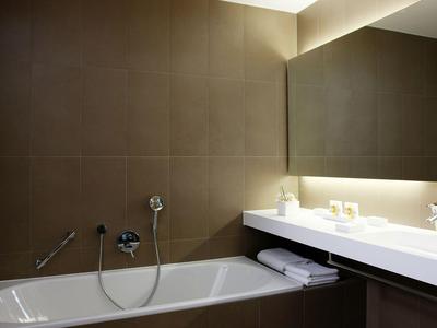Modernes Badezimmer mit Badewanne, großem Spiegel und Waschbecken mit weißen Handtüchern.