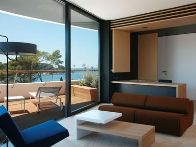 Modernes Hotelzimmer mit Terrasse, komfortablen Möbeln und Blick auf das Meer.