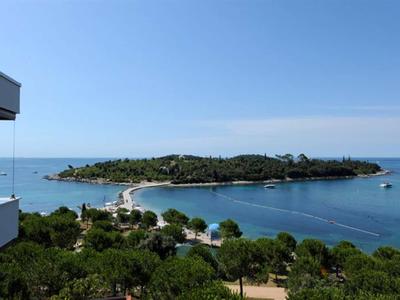 Blick auf eine kleine bewaldete Insel mit einem Gebäude im Vordergrund am Meer.