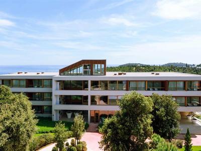 Modernes Hotelgebäude mit großer Terrasse und Blick auf das Meer bei klarem Himmel