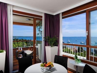Blick auf das Meer von einem Balkon mit Tisch, Stühlen und Pflanzen in einem Hotelzimmer.