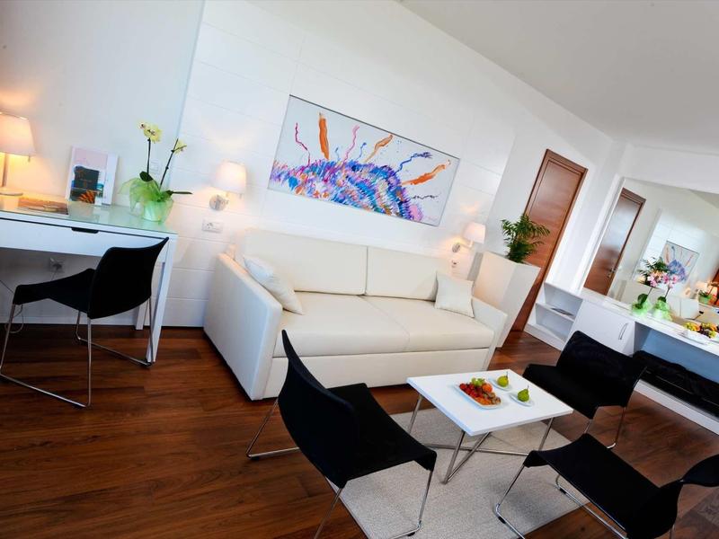 Světý, moderní obývací pokoj s bílým nábytkem a tmavými dřevěnými podlahami.