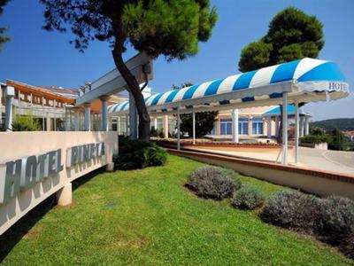 Hotelgebäude mit blauer Markise und grünem Rasen im Vordergrund bei sonnigem Wetter