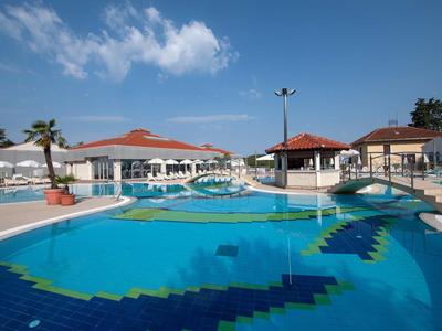Großer Außenpool mit Brücken und umgebenden Gebäuden unter blauem Himmel.