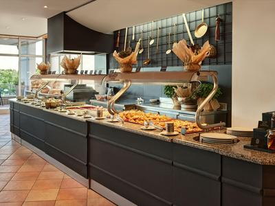 Buffet mit verschiedenen Backwaren und dekorativen Hähnen in einem modernen Hotel.
