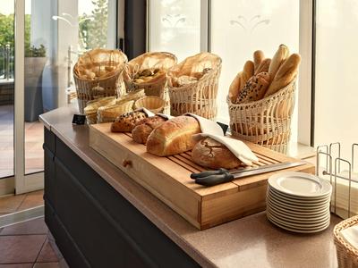 Verschiedene Brotsorten in Körben und auf einem Holzbrett in einem hellen Hotelrestaurant.
