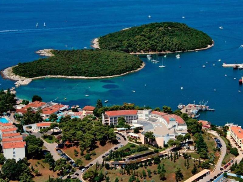 Letecký pohled na přímořské město s loděmi, ostrovy a středomořskými budovami.