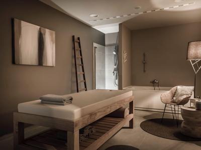 Pohodlná wellness místnost s masážním stolem, křeslem, lucernou a jemným osvětlením.