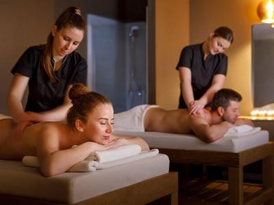 Pár přijímající masáže zad v klidné spa místnosti s teplým osvětlením.