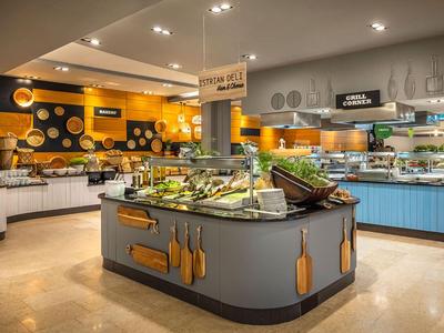 Moderní bufetová restaurace s centrálním salátovým barem a barevným designem stěn.