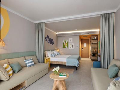 Chambre d'hôtel moderne avec deux lits, canapés, table et tons neutres.