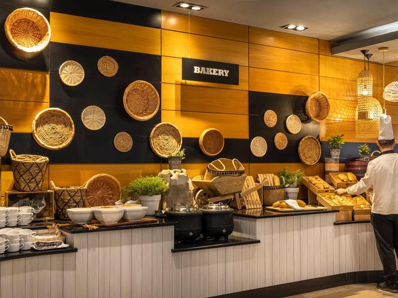 Espace buffet avec sélection de pains et paniers décoratifs au mur dans un hôtel.