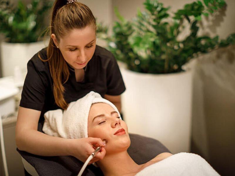 Femme recevant un soin du visage dans un spa, allongée détendue sur une table de soin.