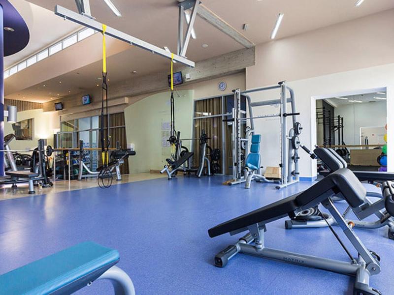 Salle de sport moderne avec appareils de musculation et mur miroir en ambiance lumineuse.