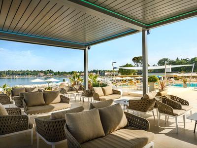 Covered terrace with comfortable chairs overlooking pool and sea