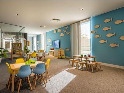 Sala de juegos infantil luminosa y moderna con muebles coloridos y decoración en la pared de un complejo vacacional.