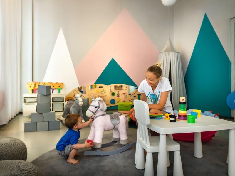 Niños juegan en una sala de juegos colorida y acogedora con muebles pequeños y juguetes.