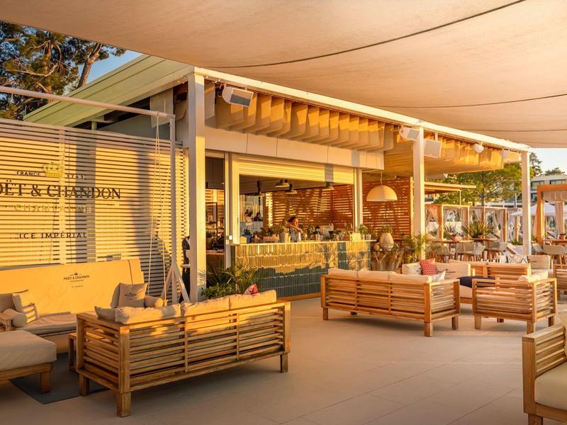 Terraza soleada del hotel con muebles modernos de madera y decoración de pared de Moët & Chandon.