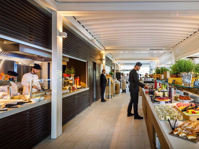 Área de desayuno moderna en hotel con buffet y huéspedes en ambiente relajado.