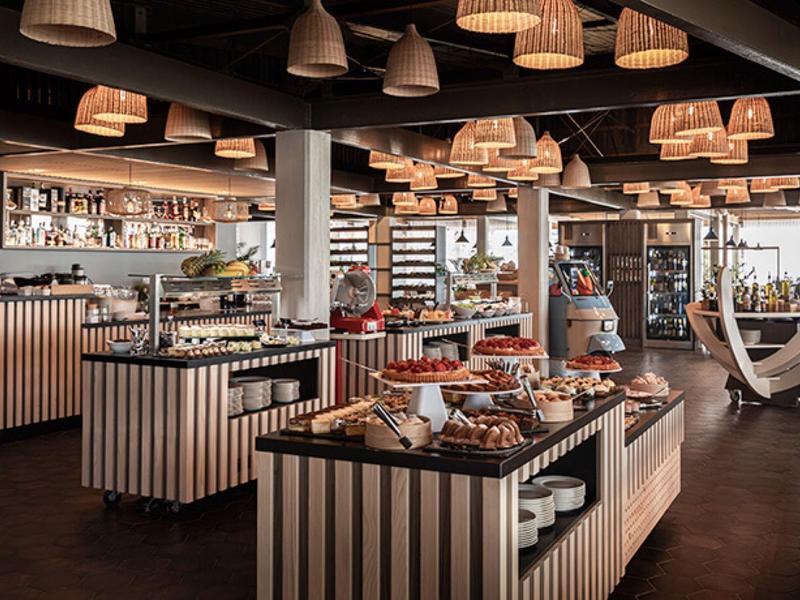 Buffet moderno y luminoso con variedad de alimentos y ambiente decorativo de madera en restaurante.