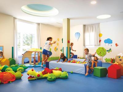 Salle de jeux colorée avec enfants jouant sur des coussins en forme d'animaux et meubles.
