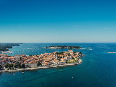 Vue aérienne d'une ville côtière avec bâtiments à toits rouges et mer bleue claire.