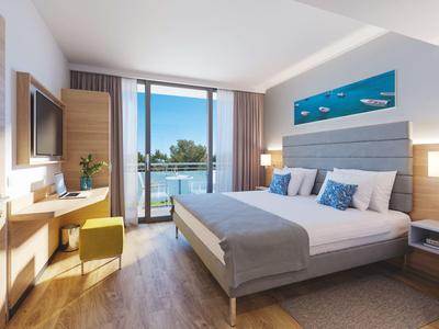 Chambre d'hôtel moderne avec lit double, balcon et vue sur la mer.