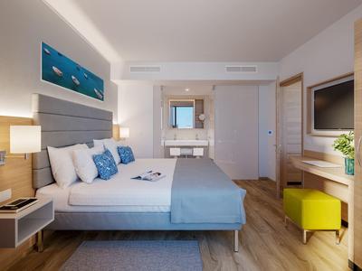 Chambre d'hôtel moderne avec grand lit, éclairage doux et décoration bleue apaisante.