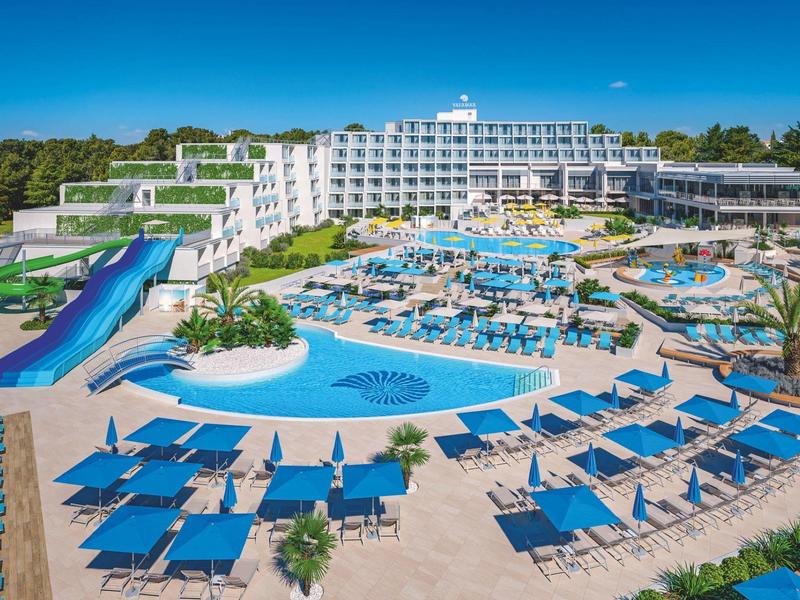 Grand complexe hôtelier avec plusieurs piscines, toboggans et de nombreux transats par temps ensoleillé.