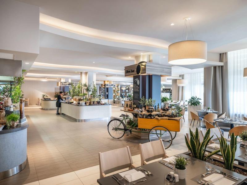 Intérieur spacieux d'un restaurant d'hôtel moderne avec décor lumineux et tables élégantes.