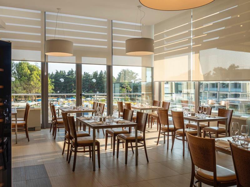 Restaurant lumineux avec mobilier en bois et grande fenêtre donnant sur l'extérieur en plein jour