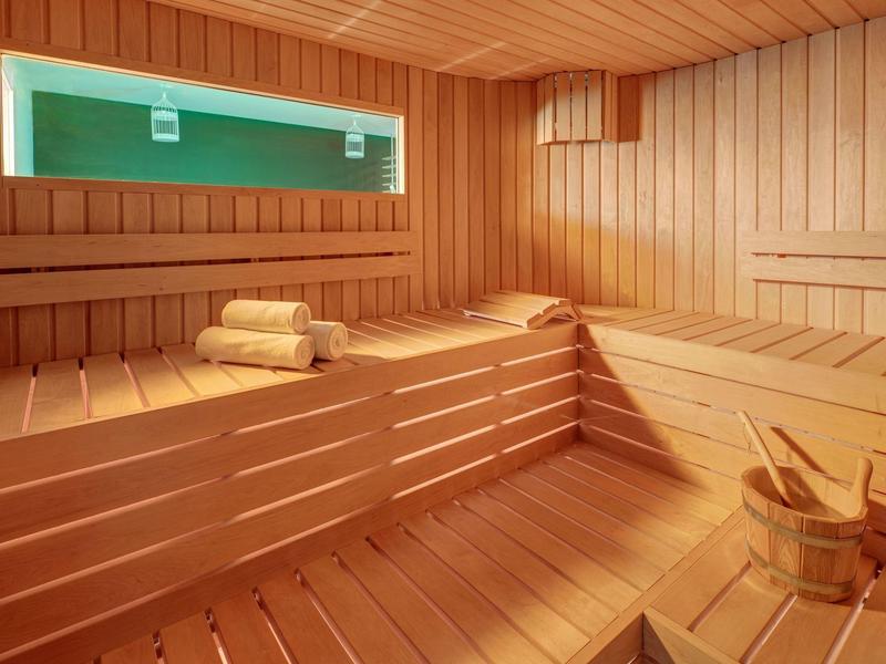 Intérieur de sauna en bois clair avec des serviettes pliées et un seau avec louche.