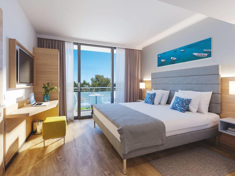 Chambre d'hôtel moderne avec lit double, balcon et vue sur la mer.