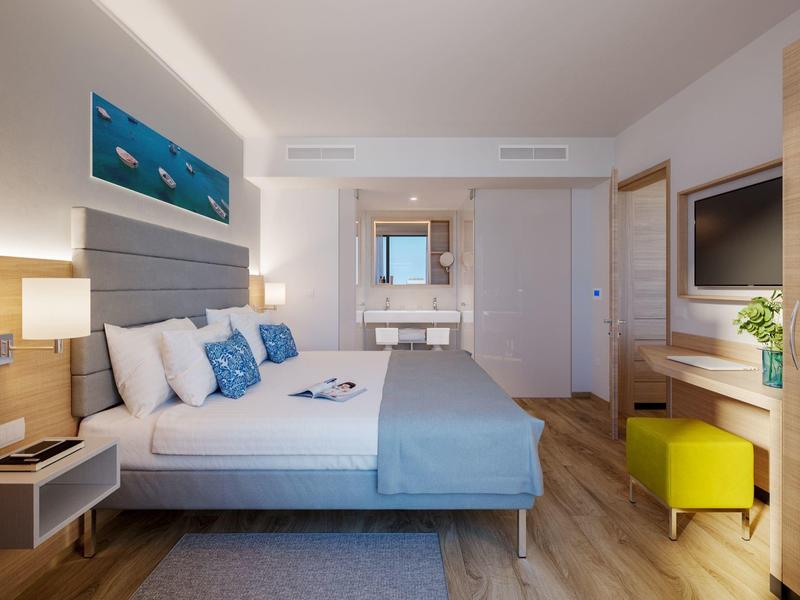 Chambre d'hôtel moderne avec grand lit, éclairage doux et décoration bleue apaisante.