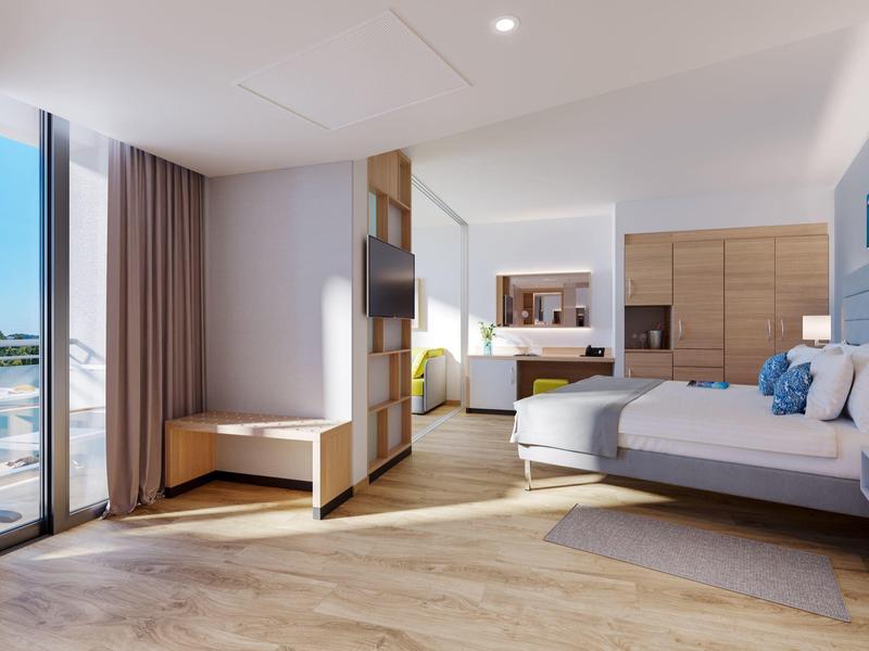 Chambre d'hôtel moderne avec lit, grande fenêtre et lumière naturelle.