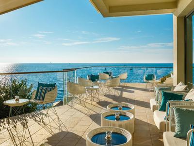 Terrasse mit Sitzgelegenheiten und Meerblick bei Sonnenschein.