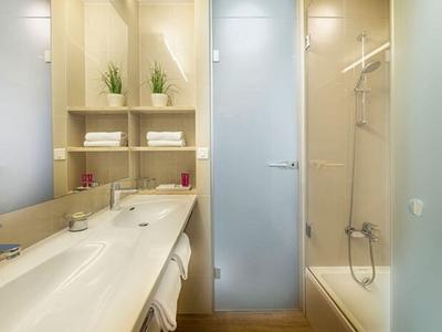 Bagno luminoso con lavandino, scaffali con asciugamani e vasca da bagno.