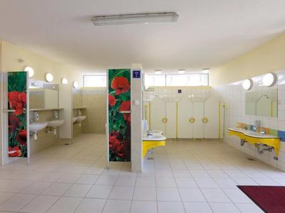 Vestuario limpio y bien iluminado con bancos amarillos y casilleros.