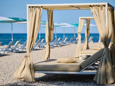 Playa con cómodas tumbonas y protección solar bajo un cielo azul junto al mar.