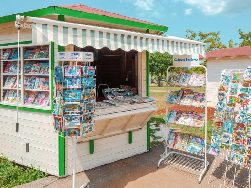 Pequeño quiosco al aire libre con numerosas postales y souvenirs bajo el sol.