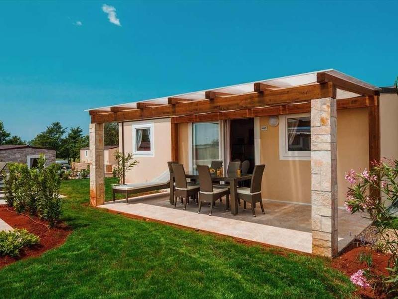 Acogedora casa de vacaciones con terraza y jardín bajo cielo azul.