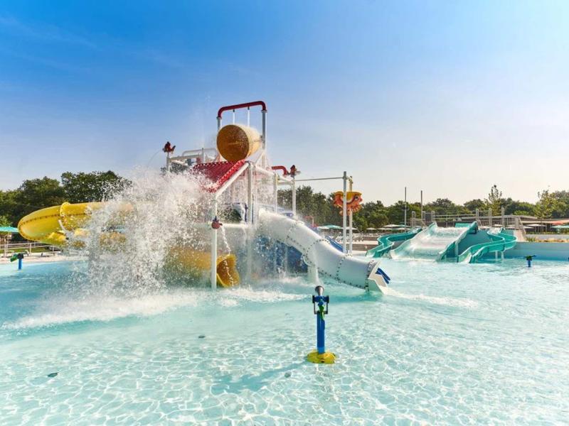 Parque acuático con toboganes y fuentes de agua en una piscina poco profunda bajo el sol