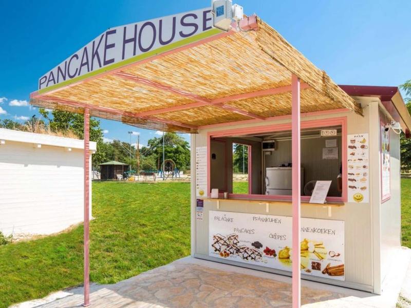 Pequeño puesto de Pancake House con techo de paja en suelo de piedra bajo clima soleado