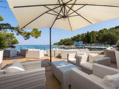 Terraza luminosa con juego de muebles de ratán blanco y vista al mar bajo cielo azul