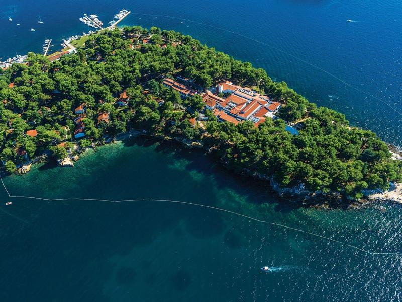 Luchtfoto van een bebost eiland met gebouwen omgeven door diepblauw water