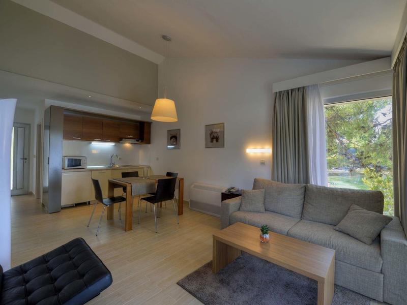 Gezellige hotelkamer met bank, bureau en uitzicht op groen.