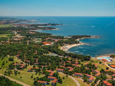 Vista aerea di una città costiera con spiagge, parchi verdi e edifici vicino al mare.
