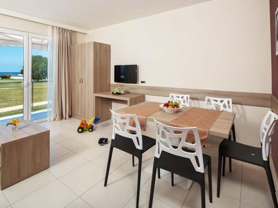 Zona pranzo moderna con tavolo, sedie e TV accanto alla porta della terrazza con vista sull'esterno