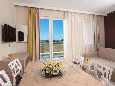 Sala da pranzo luminosa con tavolo, sedie, divano e balcone con vista sui campi.